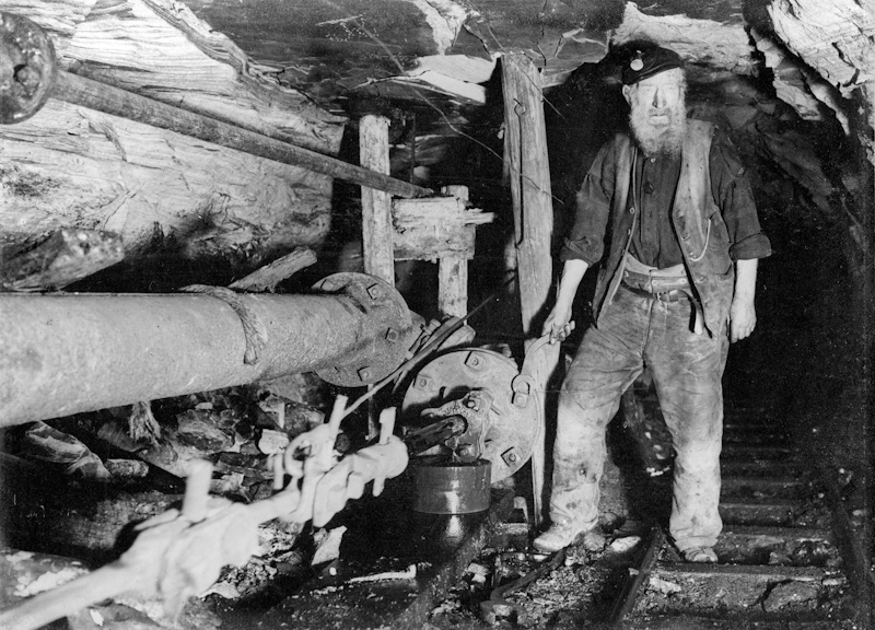 An engineer maintains a crank pump underground in Camp Colliery near Motherwell, around 1910.