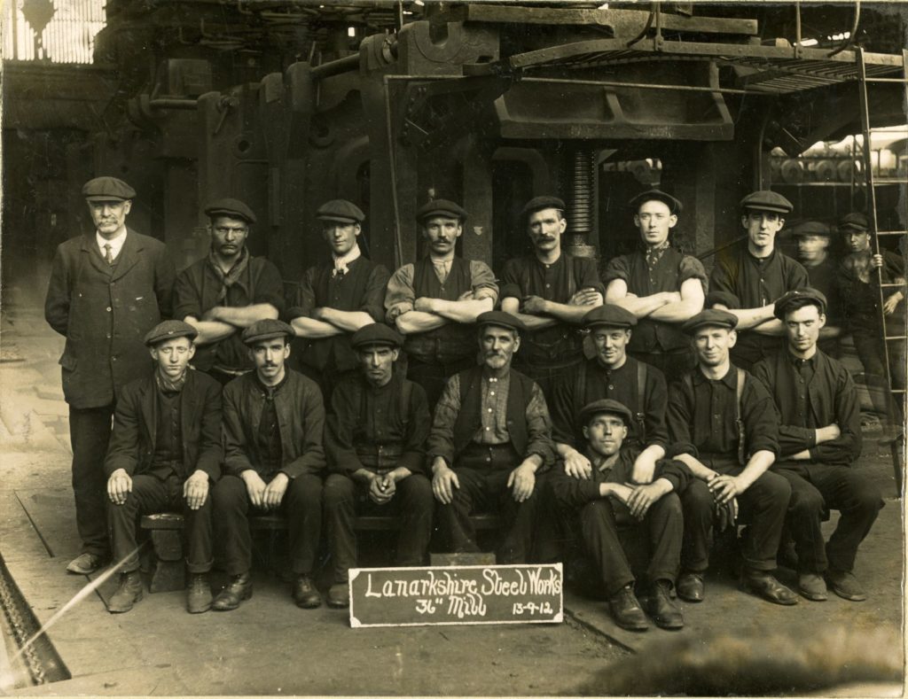 A rolling mill team at the Lanarkshire Steel Works, 1912. The metal plating on the ground is to protect the floor from the red-hot steel as it emerges from the mill rollers.